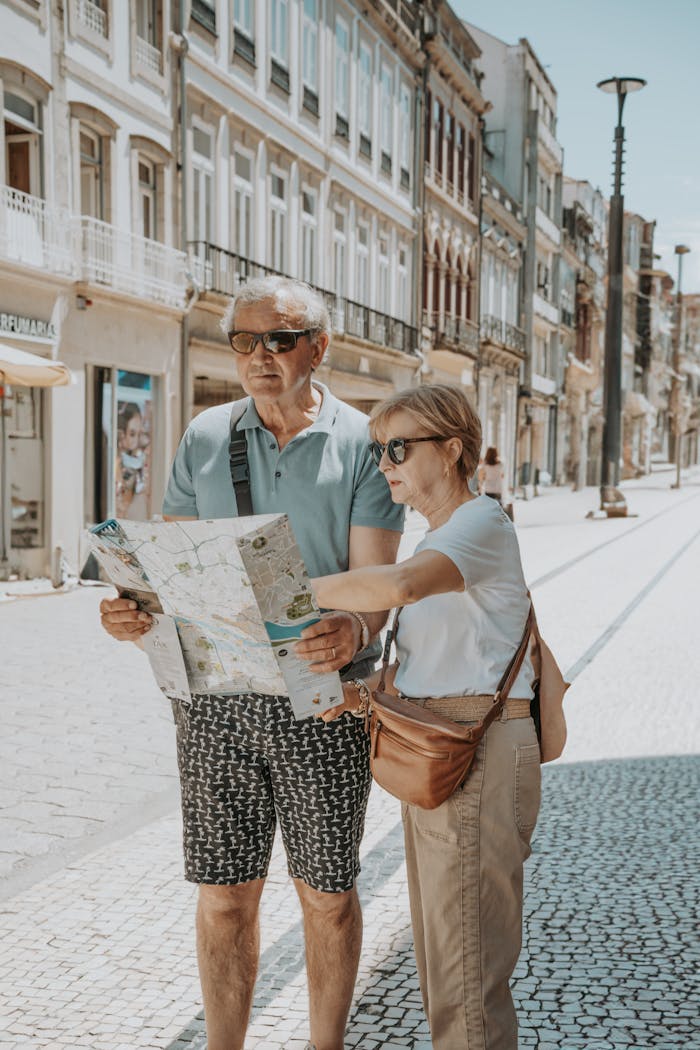 services-03 Senior couple in summer attire navigates with a map on a sunny Porto street.