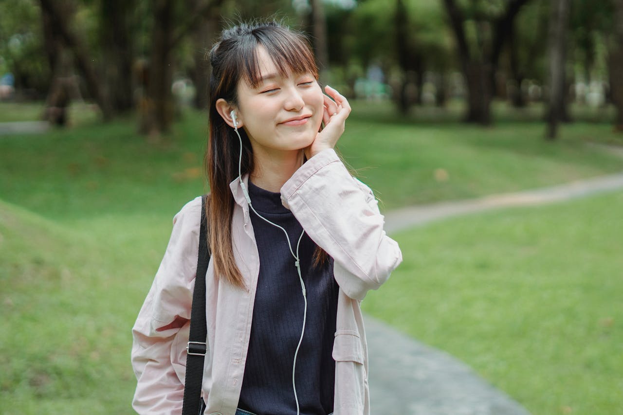 Cheerful woman listening to music in park, enjoying leisure time.